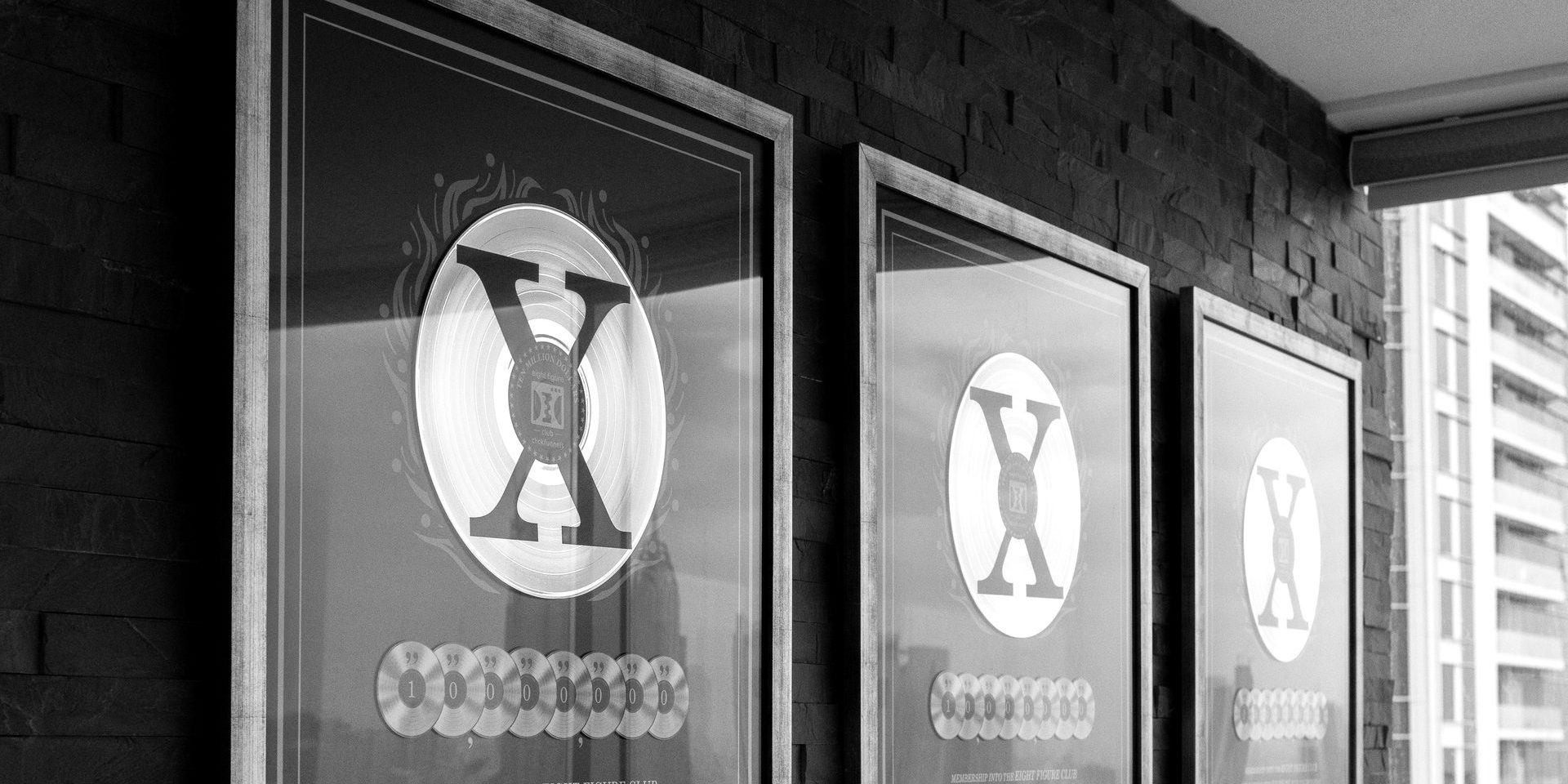 Drei gerahmte 8-Figure Awards an einer dunklen Steinwand