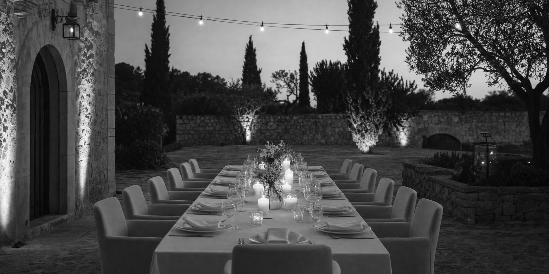 Eine lange, festlich gedeckte Tafel im Garten am Abend