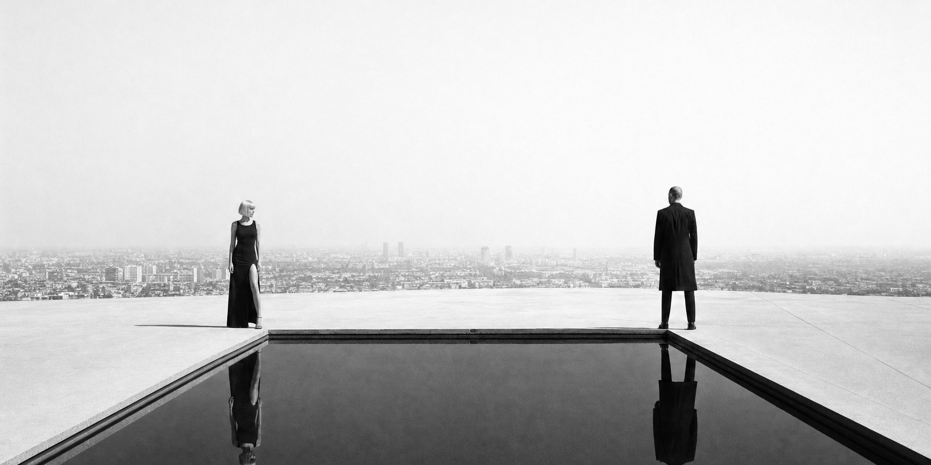 Ein Mann steht am Rand eines Pools hoch über einer Stadt